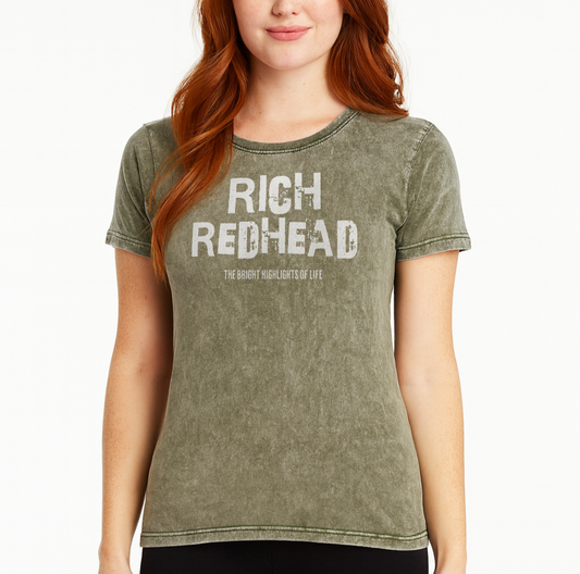 redhead wears an army green acid-wash unisex denim T-shirt with a distressed vintage look. The shirt features the bold white text “RICH REDHEAD” in a weathered Ed Gein font, with the tagline “THE BLONDE HIGHLIGHTS OF LIFE” in smaller uppercase letters below. The shirt has short sleeves, a crew neckline, and visible seam detailing for a rugged, casual style. Branded Redblonde on inside neck and right sleeve