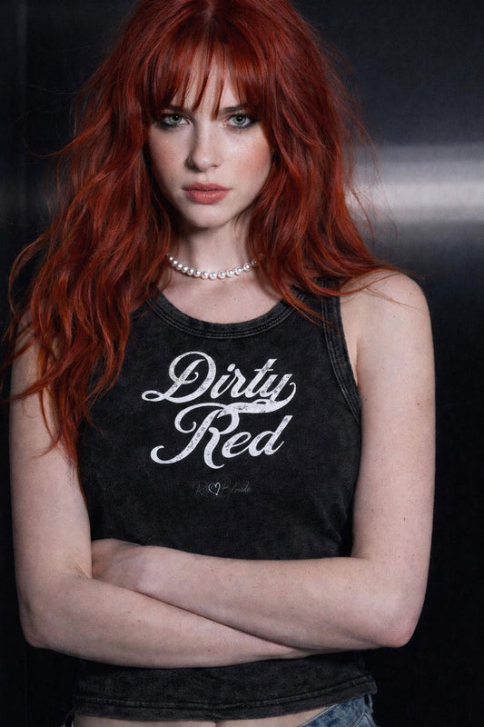 Redhead wears a Black snow-wash tank top with raw-edge seams and the phrase ‘Dirty Red’ printed in vintage Milkstore white font across the chest, featuring the RedBlonde logo underneath