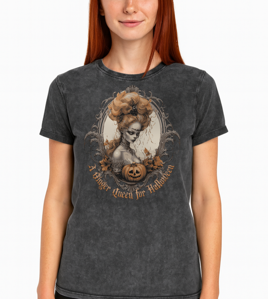 redhead ginger woman wears a Black acid-wash unisex T-shirt featuring a gothic-style illustration of ginger-haired woman with an elaborate beehive hairstyle, framed by ornate scrollwork, autumn leaves, and a carved pumpkin. The design is captioned with the text ‘A Blonde Queen for Halloween’ in vintage Dark Angle lettering. Branded RedBlonde in red on inside neck and right sleeve