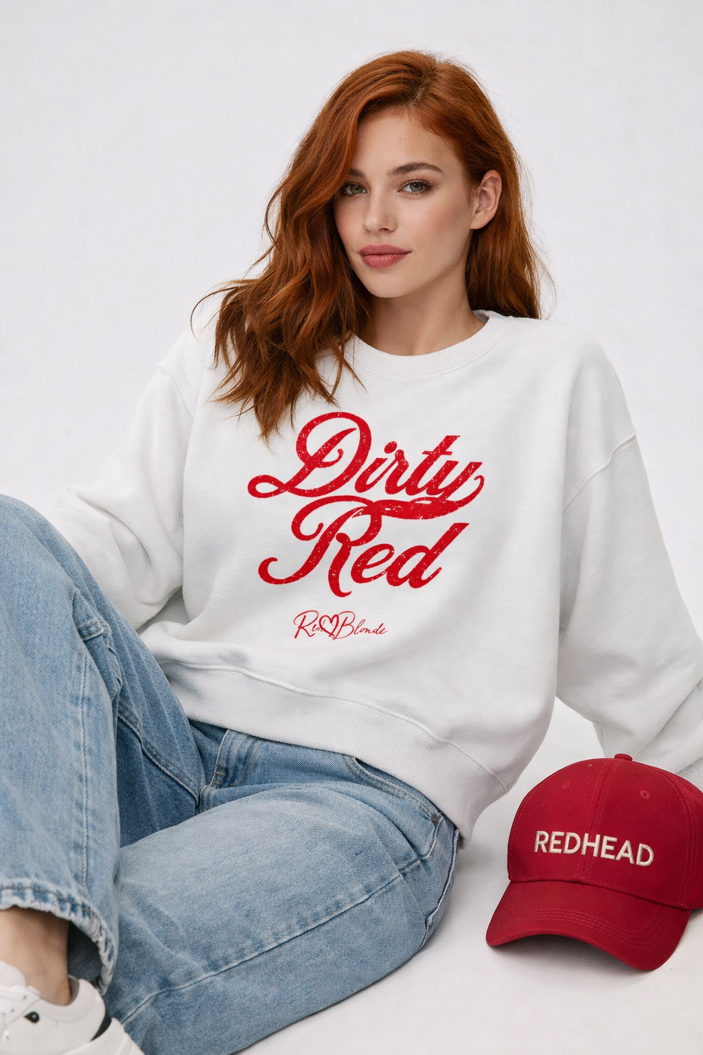 redhead wears white Classic relaxed fit premium unisex sweatshirt with the playful slogan ‘Dirty Red’ in red milk-store font, signed off RedBlonde. 