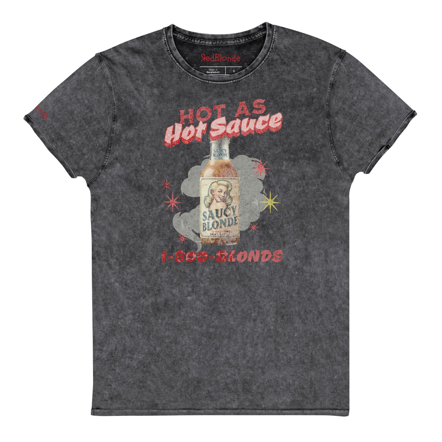 flatlay of a relaxed dark grey denim-wash t-shirt with a retro American-vintage pop-art graphic featuring a bottle of sauce with Saucy Blonde on it and the words Hot As hot Sauce. branded with redblonde london in red on the inside neck and right shoulder