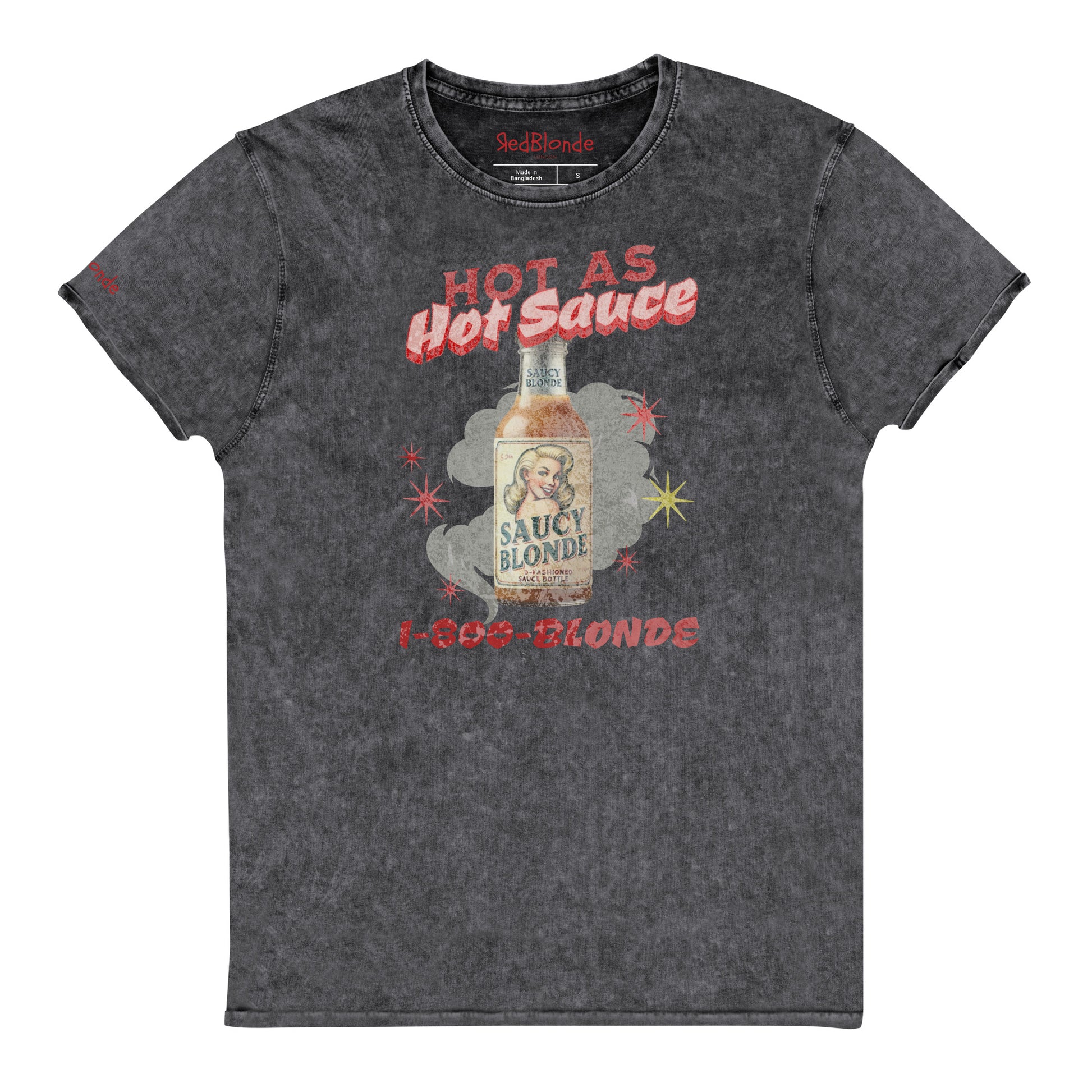 flatlay of a relaxed dark grey denim-wash t-shirt with a retro American-vintage pop-art graphic featuring a bottle of sauce with Saucy Blonde on it and the words Hot As hot Sauce. branded with redblonde london in red on the inside neck and right shoulder
