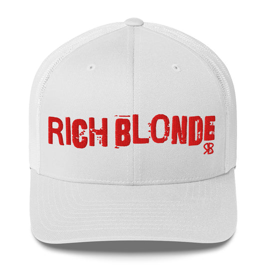white mesh-back trucker cap with the bold distressed text “RICH BLONDE” embroidered in red across the front, and a small red “RB” logo detail beneath the text. The cap has a structured front panel and curved brim