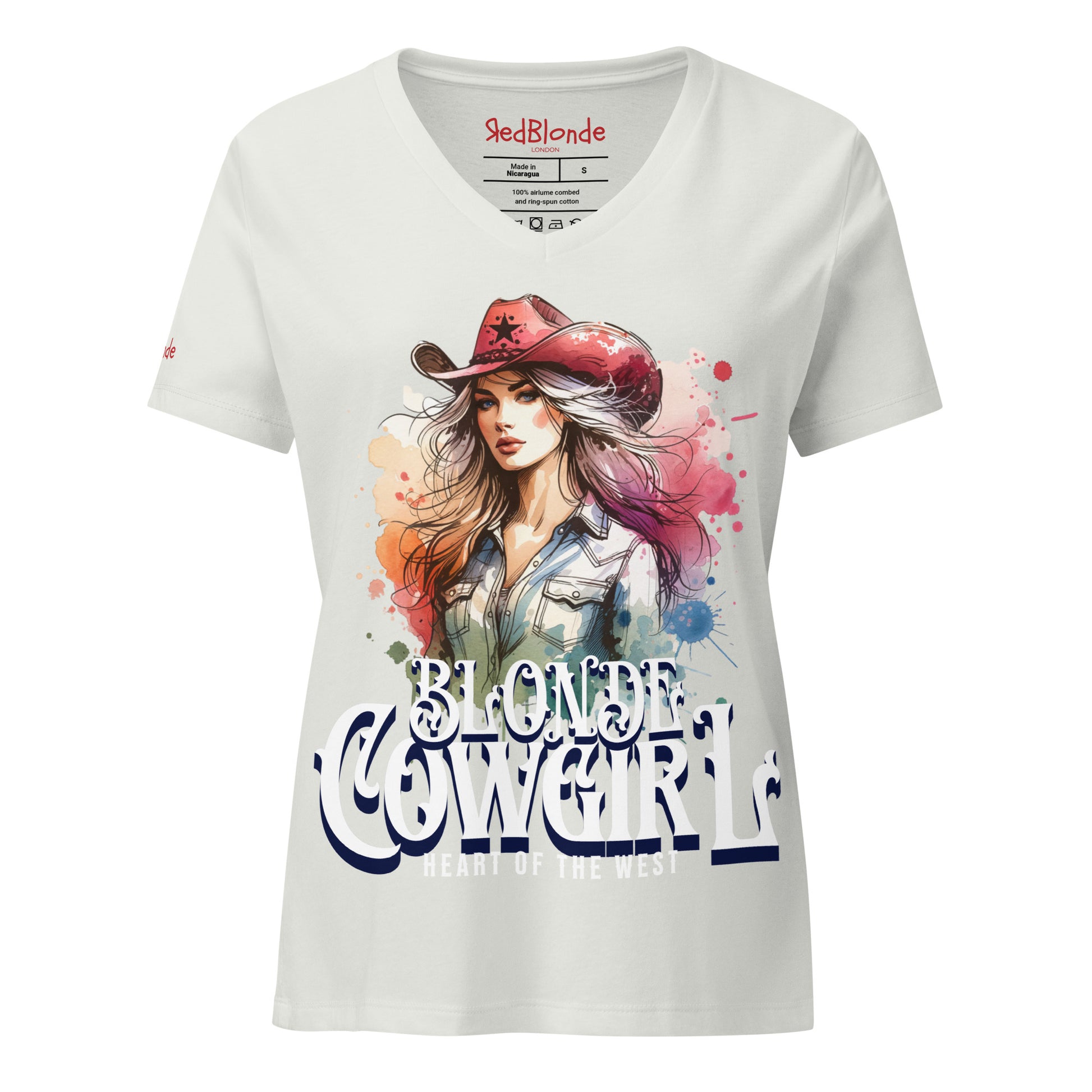 silver V-neck women’s T-shirt with a colorful graphic of a stylish blonde cowgirl wearing a red cowboy hat and denim shirt, paired with the bold text “Blonde Cowgirl” and “Heart of the West” in white western-style font. Branded RedBlonde on inside neck and right sleeve