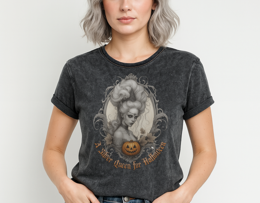 Black acid-wash unisex T-shirt featuring a gothic-style illustration of a silver-haired woman with an elaborate beehive hairstyle, framed by ornate scrollwork, autumn leaves, and a carved pumpkin. The design is captioned with the text ‘A Silver Queen for Halloween’ in vintage Dark Angle lettering. Branded RedBlonde in red on inside neck and right sleeve