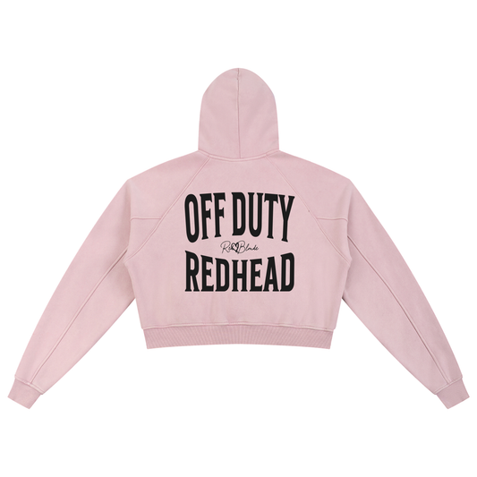 “Back view of a soft pink cropped hoodie with a hood and long sleeves, featuring large black ‘OFF DUTY REDHEAD' text and a small RedBlonde logo on the back.”