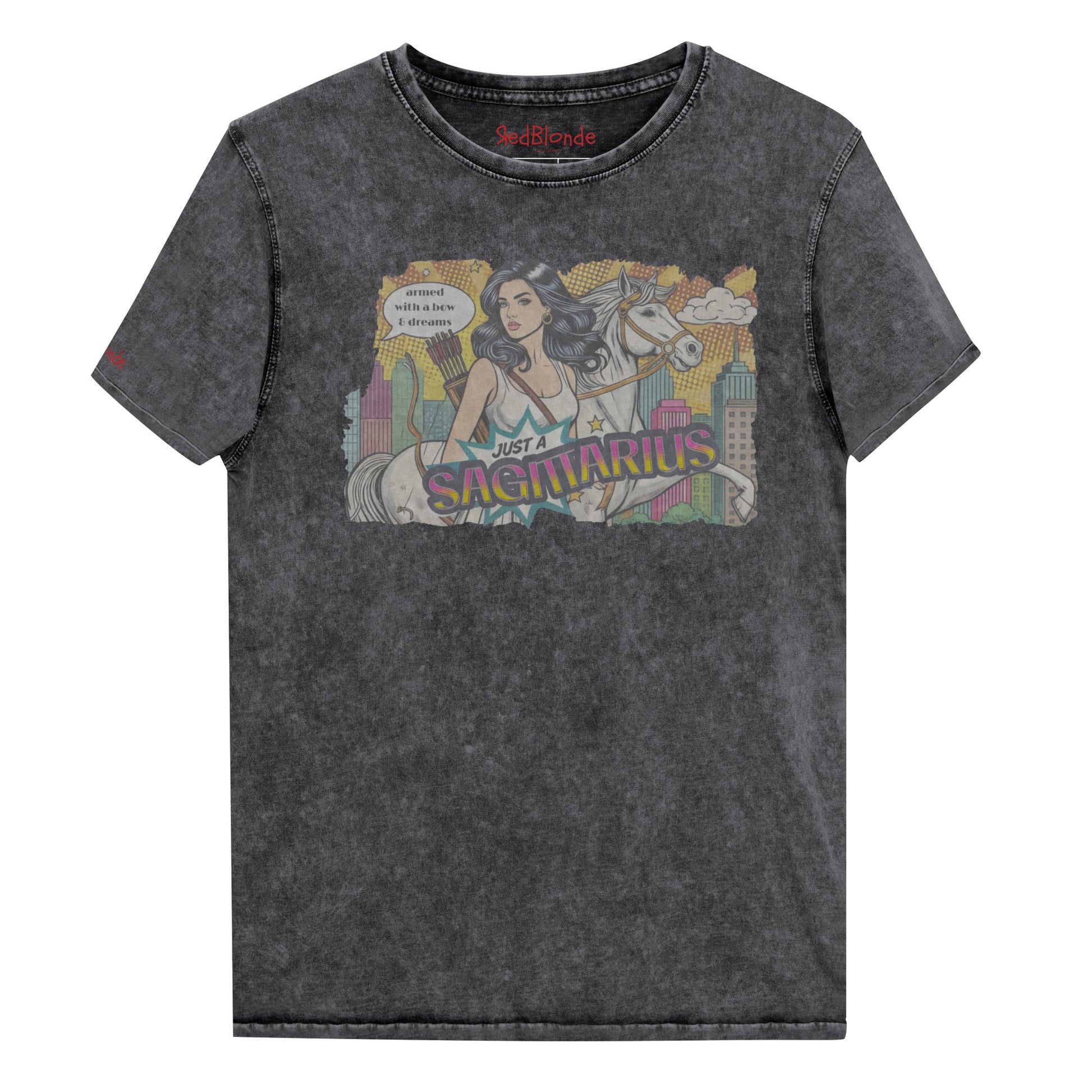 Flatlay of a unisex black denim wash vintage t-shirt with a retro pop-art Sagittarius graphic featuring a black haired woman, with bow & arrows, white stallion, and a city backdrop, captioned ‘Just a Sagittarius, armed with a bow & dreams'. Branded RedBlonde on the inside neck and right sleeve