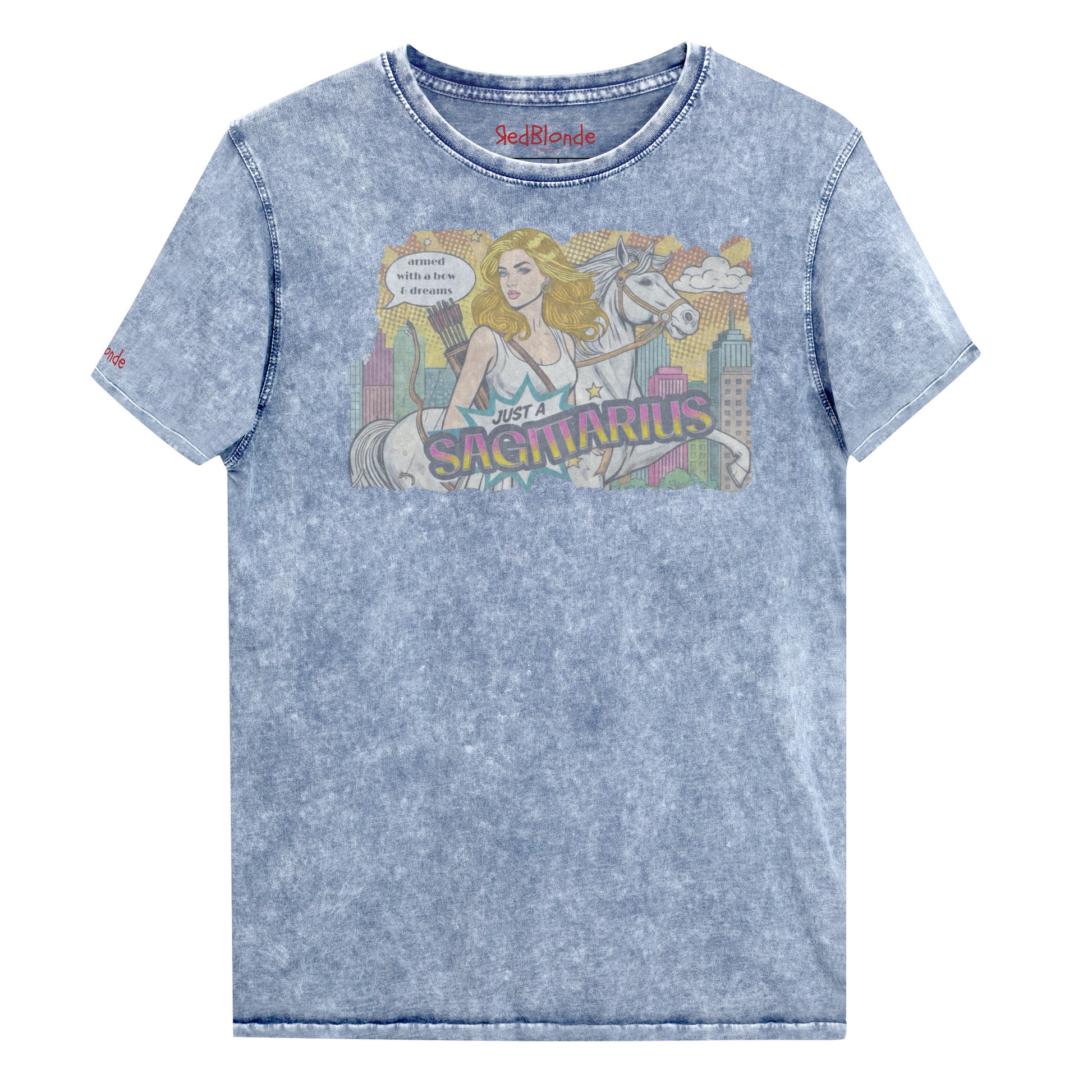 Flatlay of a unisex blue denim wash vintage t-shirt with a retro pop-art Blonde Sagittarius graphic featuring a blonde woman, with bow & arrows, white stallion, and a city backdrop, captioned ‘Just a Sagittarius, armed with a bow & dreams'. Branded RedBlonde on the inside neck and right sleeve