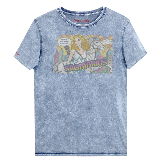 Flatlay of a unisex blue denim wash vintage t-shirt with a retro pop-art Blonde Sagittarius graphic featuring a blonde woman, with bow & arrows, white stallion, and a city backdrop, captioned ‘Just a Sagittarius, armed with a bow & dreams'. Branded RedBlonde on the inside neck and right sleeve