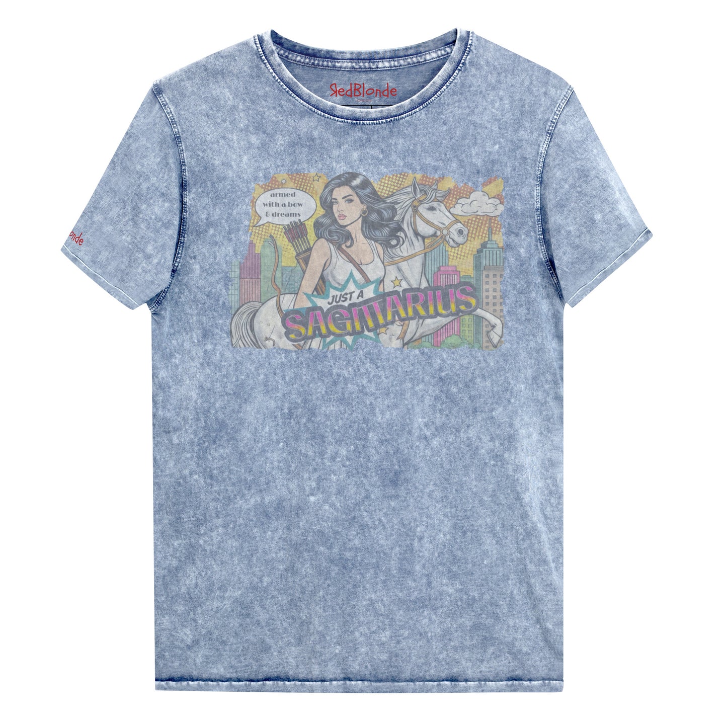 Flatlay of a unisex blue denim wash vintage t-shirt with a retro pop-art Sagittarius graphic featuring a black haired woman, with bow & arrows, white stallion, and a city backdrop, captioned ‘Just a Sagittarius, armed with a bow & dreams'. Branded RedBlonde on the inside neck and right sleeve