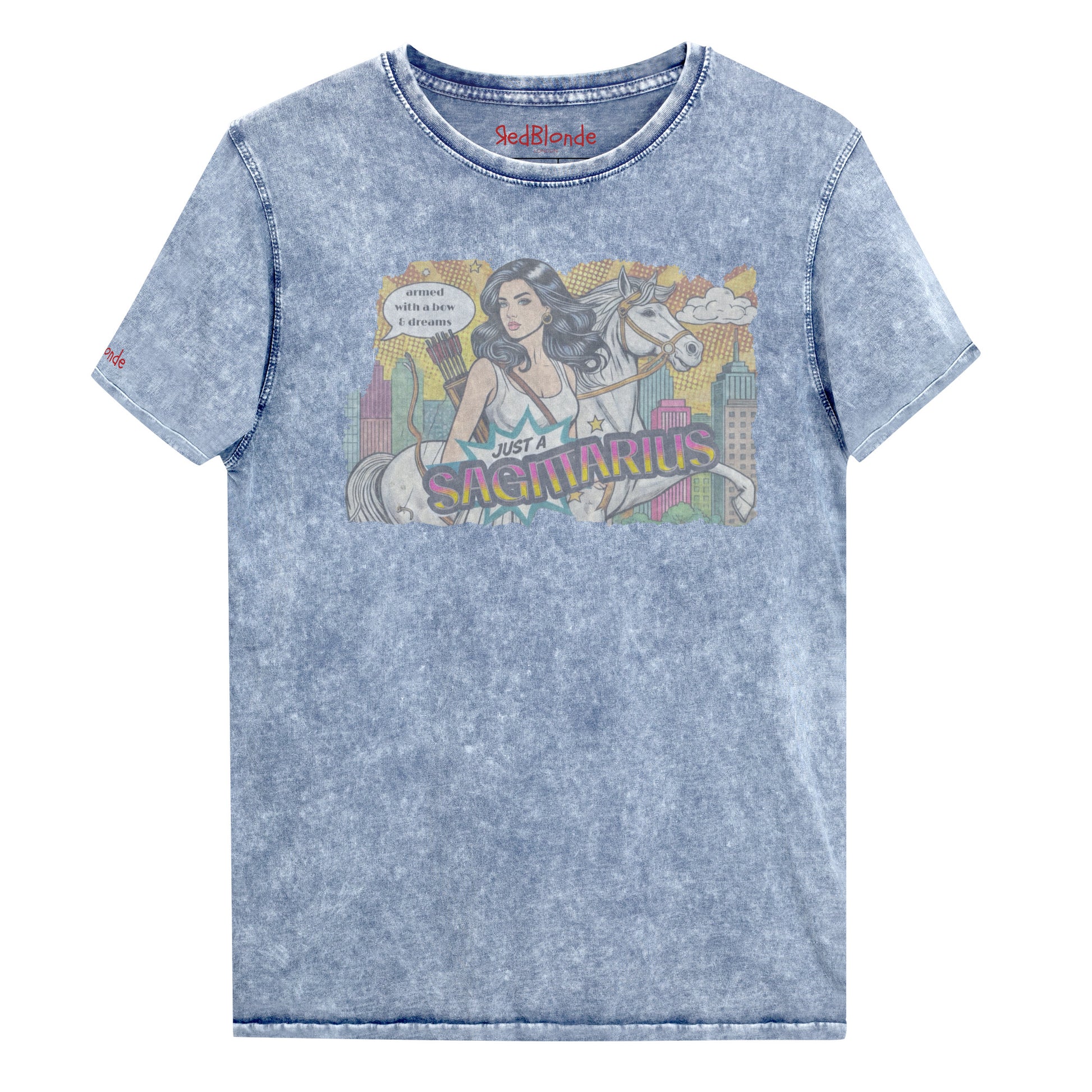 Flatlay of a unisex blue denim wash vintage t-shirt with a retro pop-art Sagittarius graphic featuring a black haired woman, with bow & arrows, white stallion, and a city backdrop, captioned ‘Just a Sagittarius, armed with a bow & dreams'. Branded RedBlonde on the inside neck and right sleeve