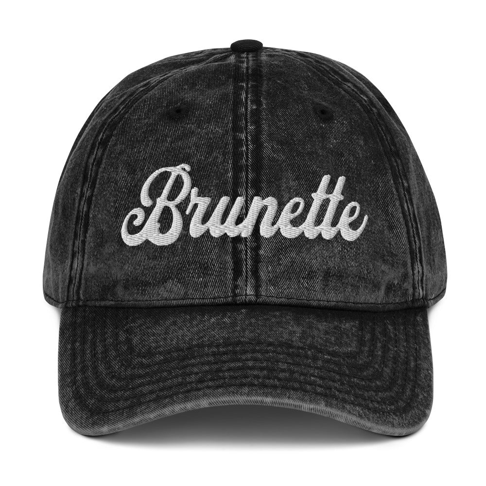 flatlay of vintage black denim wash effect baseball cap with the word 'Brunette' embroidered on the front in white adventure type script font 