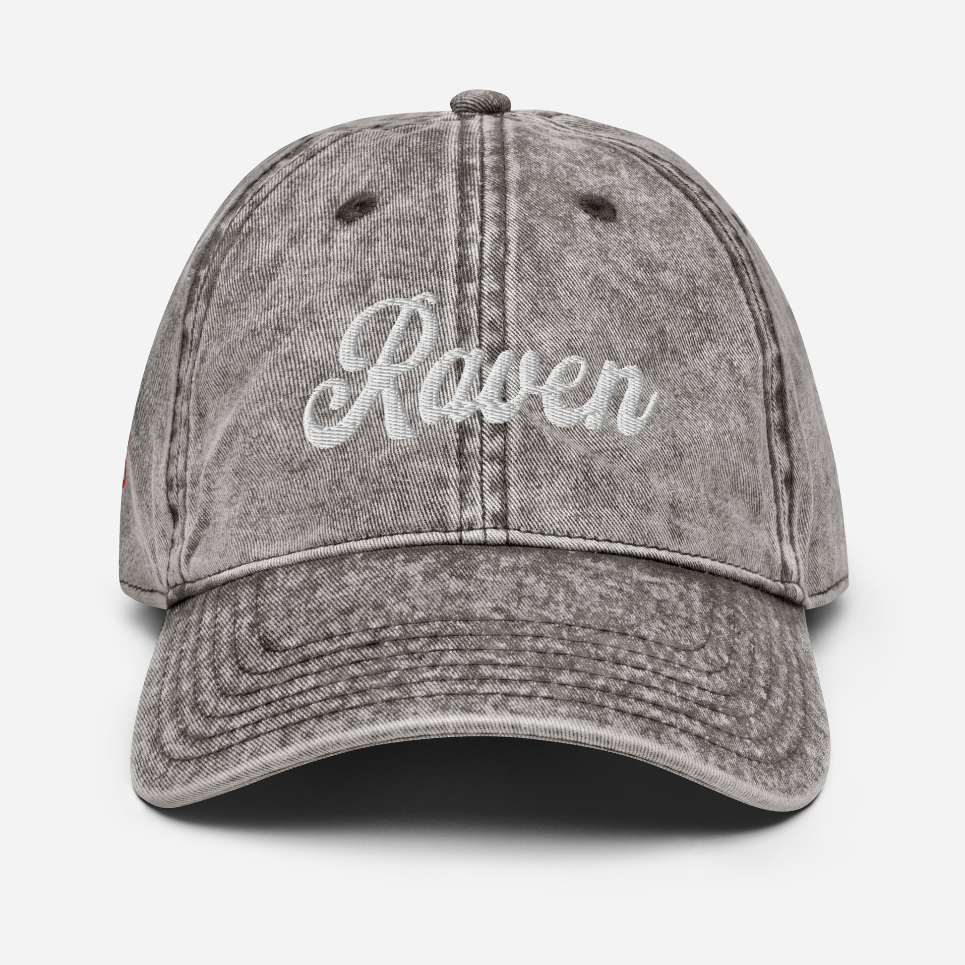 flatlay of vintage black / grey denim wash effect baseball cap with the word 'Raven' embroidered on the front in white adventure type script font
