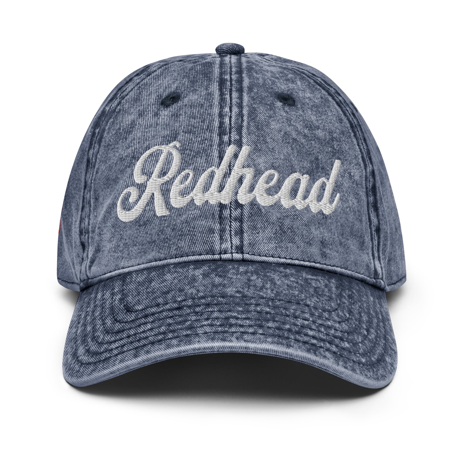 flatlay of vintage blue denim wash effect baseball cap with the word 'Redhead' embroidered on the front in white adventure type script font 