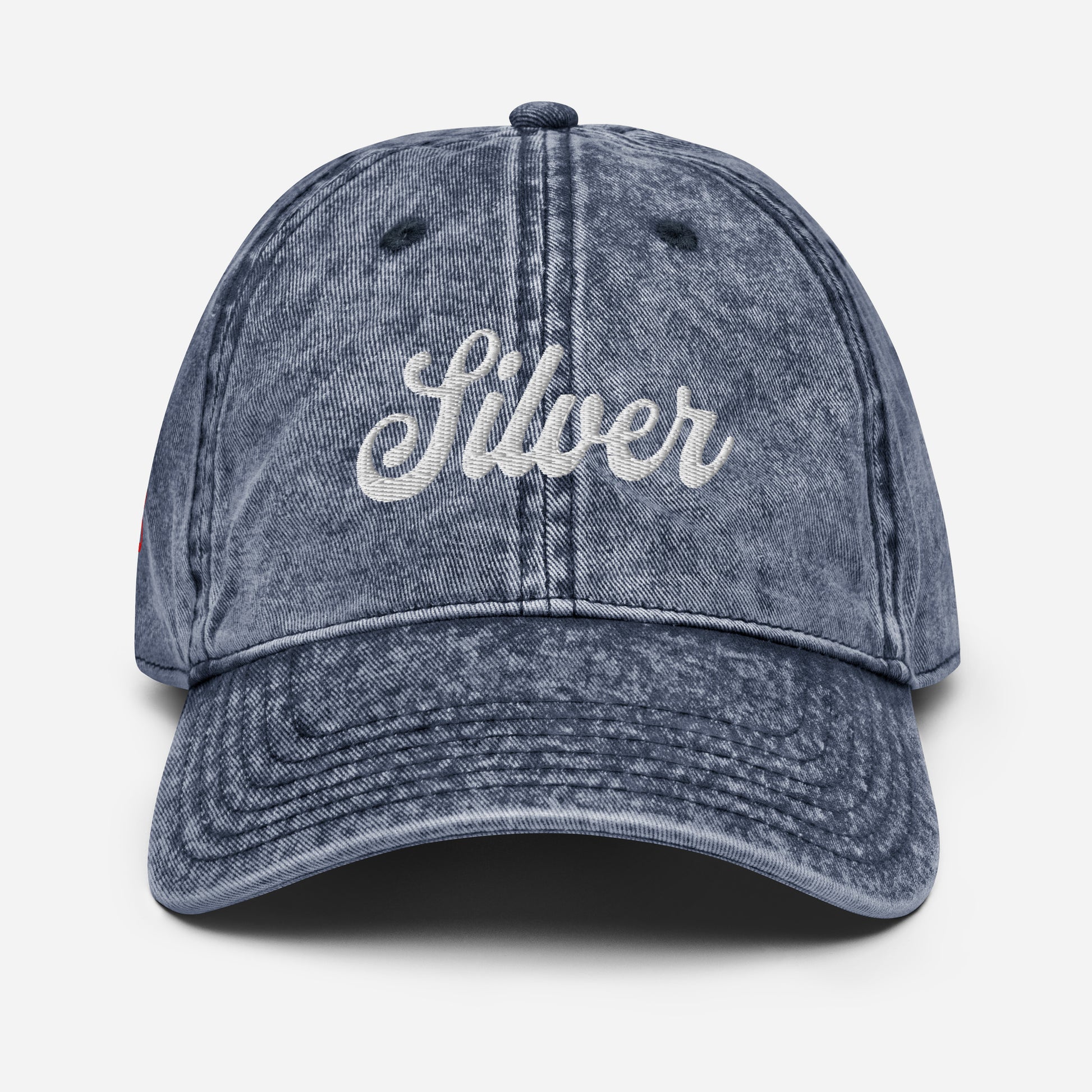 flatlay of vintage blue denim wash effect baseball cap with the word 'Silver' embroidered on the front in white adventure type script font 
