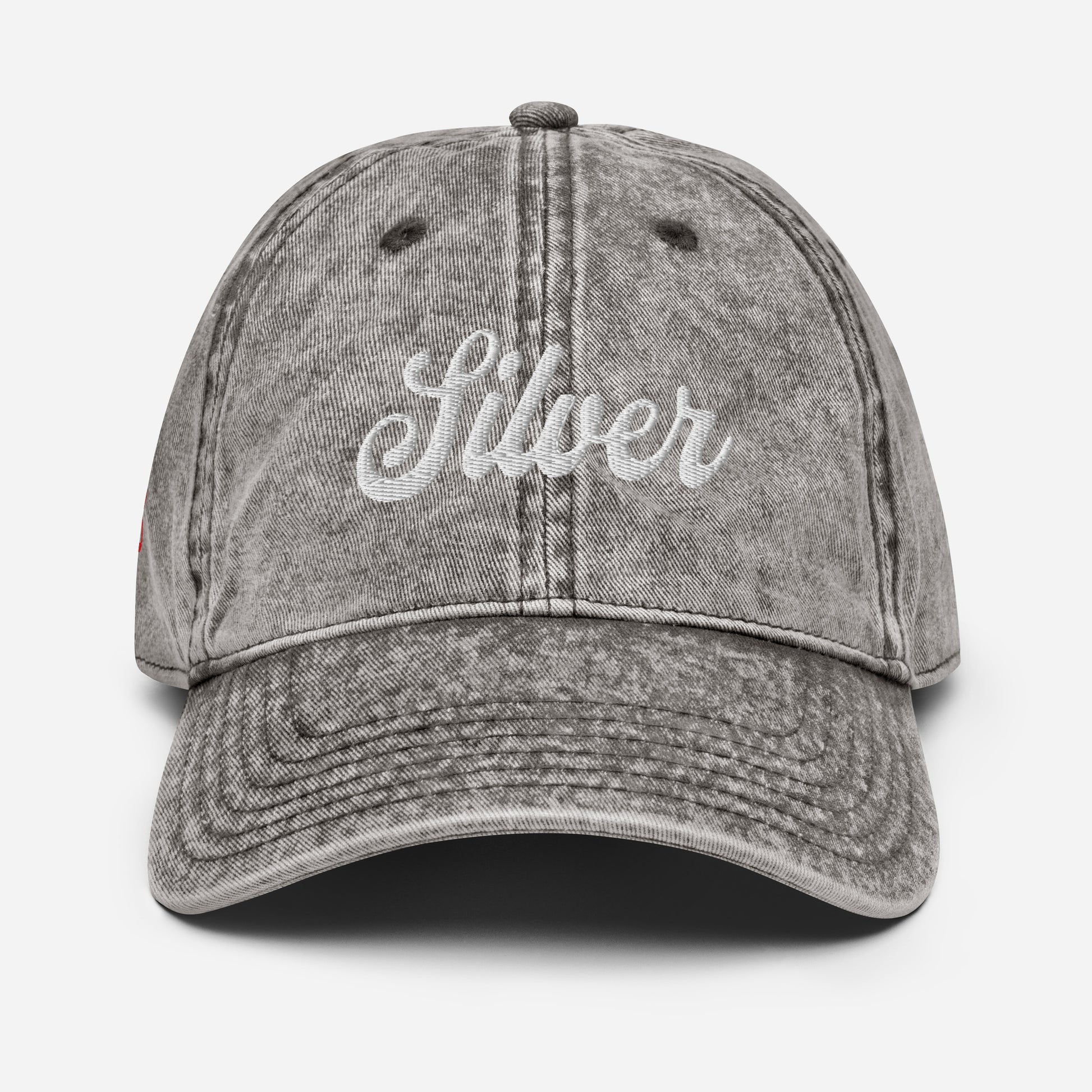 flatlay of vintage grey denim wash effect baseball cap with the word 'Silver' embroidered on the front in white adventure type script font 