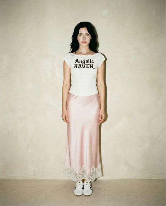 white wide-neck t-shirt with white gothic New Rockstar text reading “Angelic Raven” across the chest.