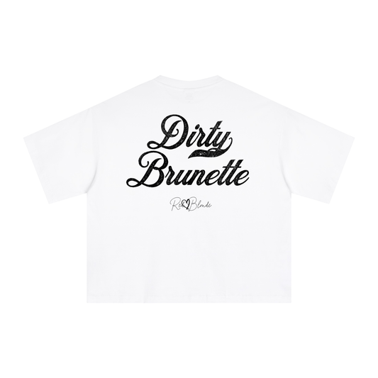 The back of a white oversized boxy short-sleeve T-shirt laid flat on a white background. Large distressed black Milkstore 01 script text reads “Dirty Brunette,” with a small cursive “RedBlonde” logo beneath the main graphic.
