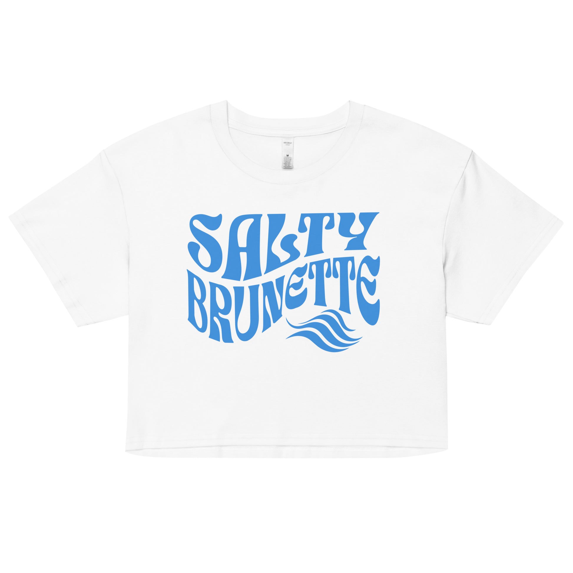 Flatlay of a white loose women's crop top t-shirt with the words ‘Salty Brunette’ in blue retro 70s font
