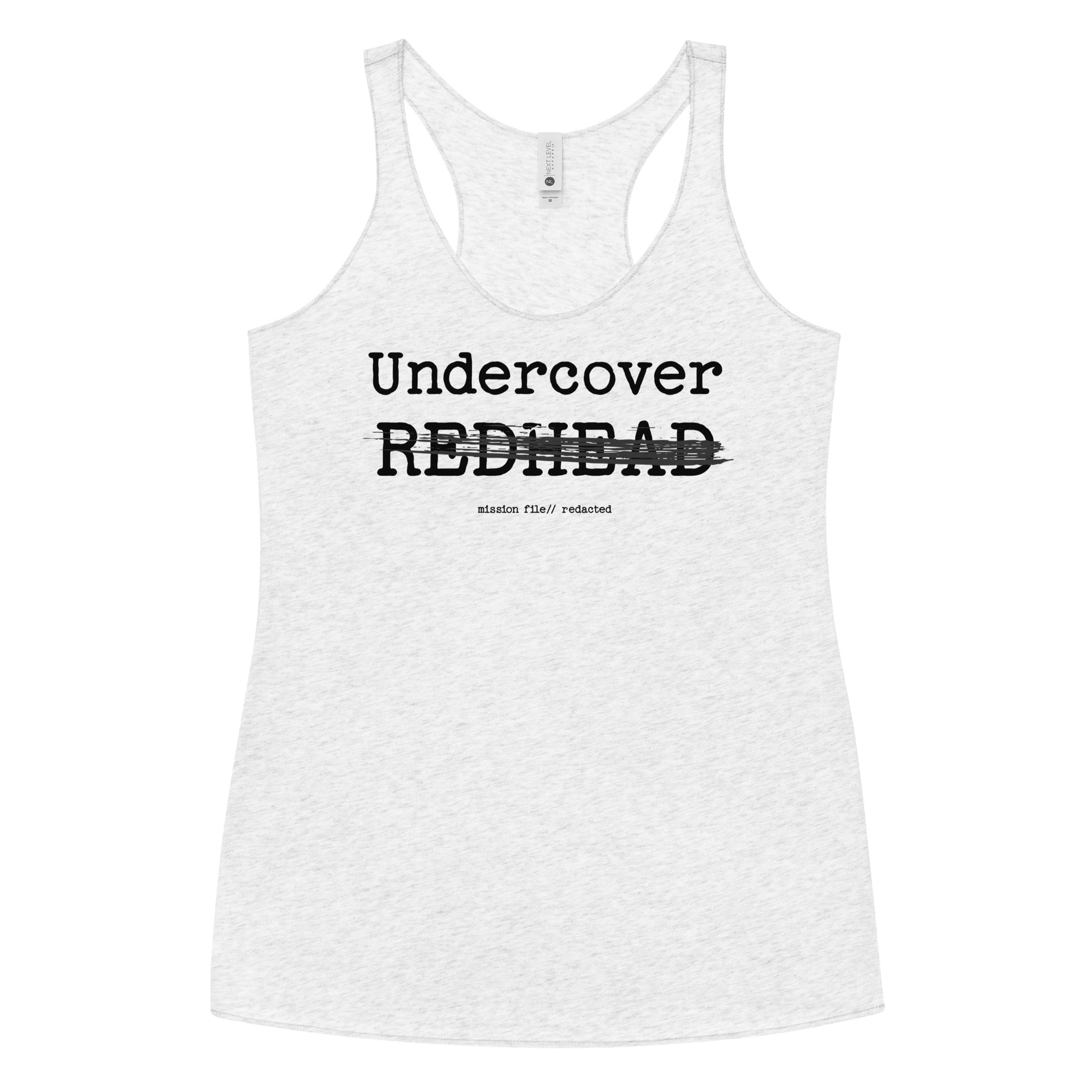 A white racerback tank featuring a bold black text reading “Undercover REDHEAD” with “REDHEAD” partially struck through by a horizontal black bar. Beneath it, smaller text says “mission file // redacted” along with a subtle RedBlonde logo. Branded RedBlonde London in red on the reverse