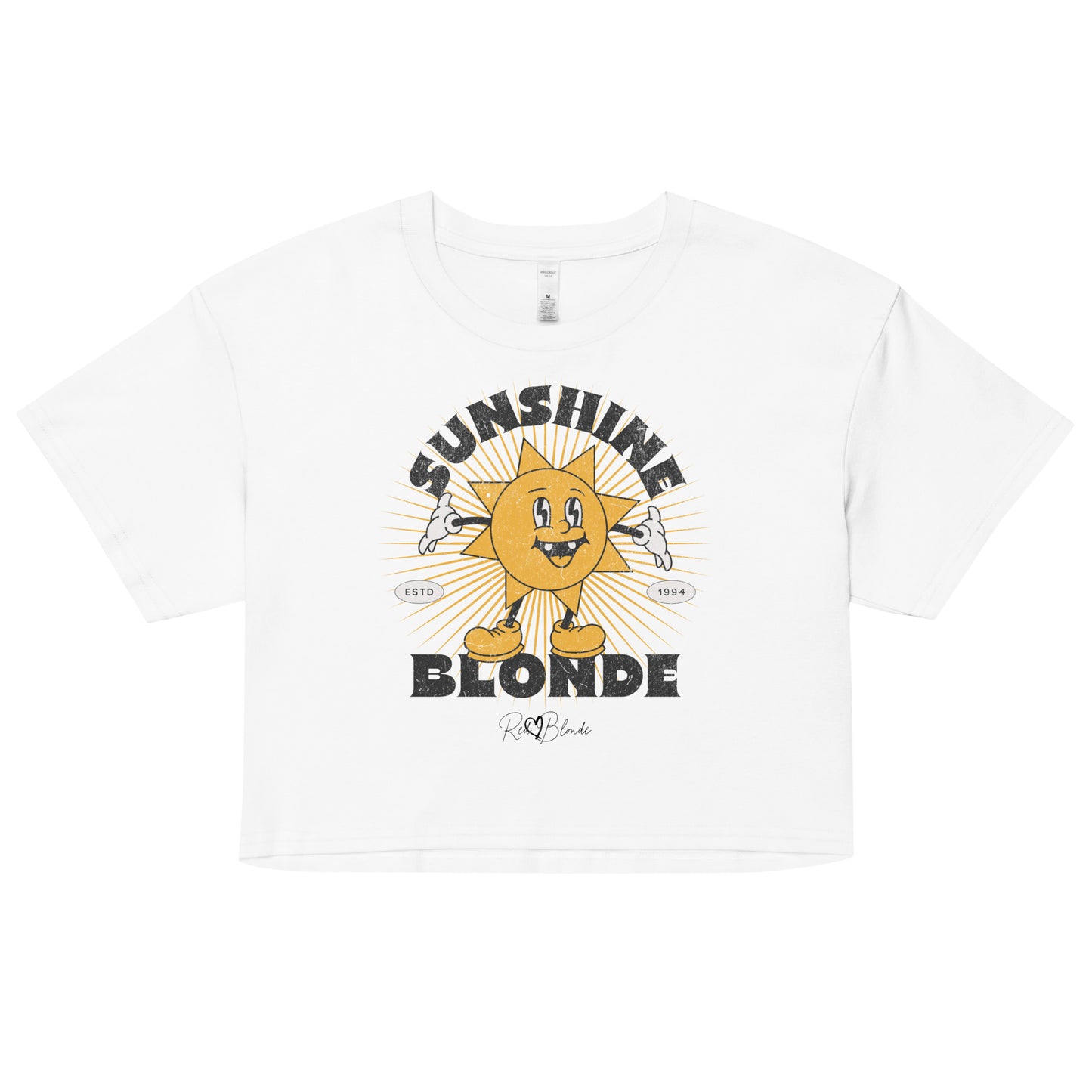 White women’s crop top with a retro cartoon-style yellow sun character, smiling with open arms, surrounded by radiant sunbeams. The text reads ‘Sunshine Blonde’ in bold vintage Belzebuth lettering, with small details including ‘ESTD 1994’ and the RedBlonde signature logo beneath."