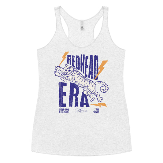 white vintage-style racerback tank features a large, stylized illustration of a tiger leaping forward in pale purple and white. Bold, distressed text above and below reads “REDHEAD ERA” in uppercase purple letters, with two orange lightning bolts flanking the text. Beneath the lion in small purple letters are the phrases “Tiger-like strength” and “True power.” RedBlonde with a heart small signature-like logo appears below the text.